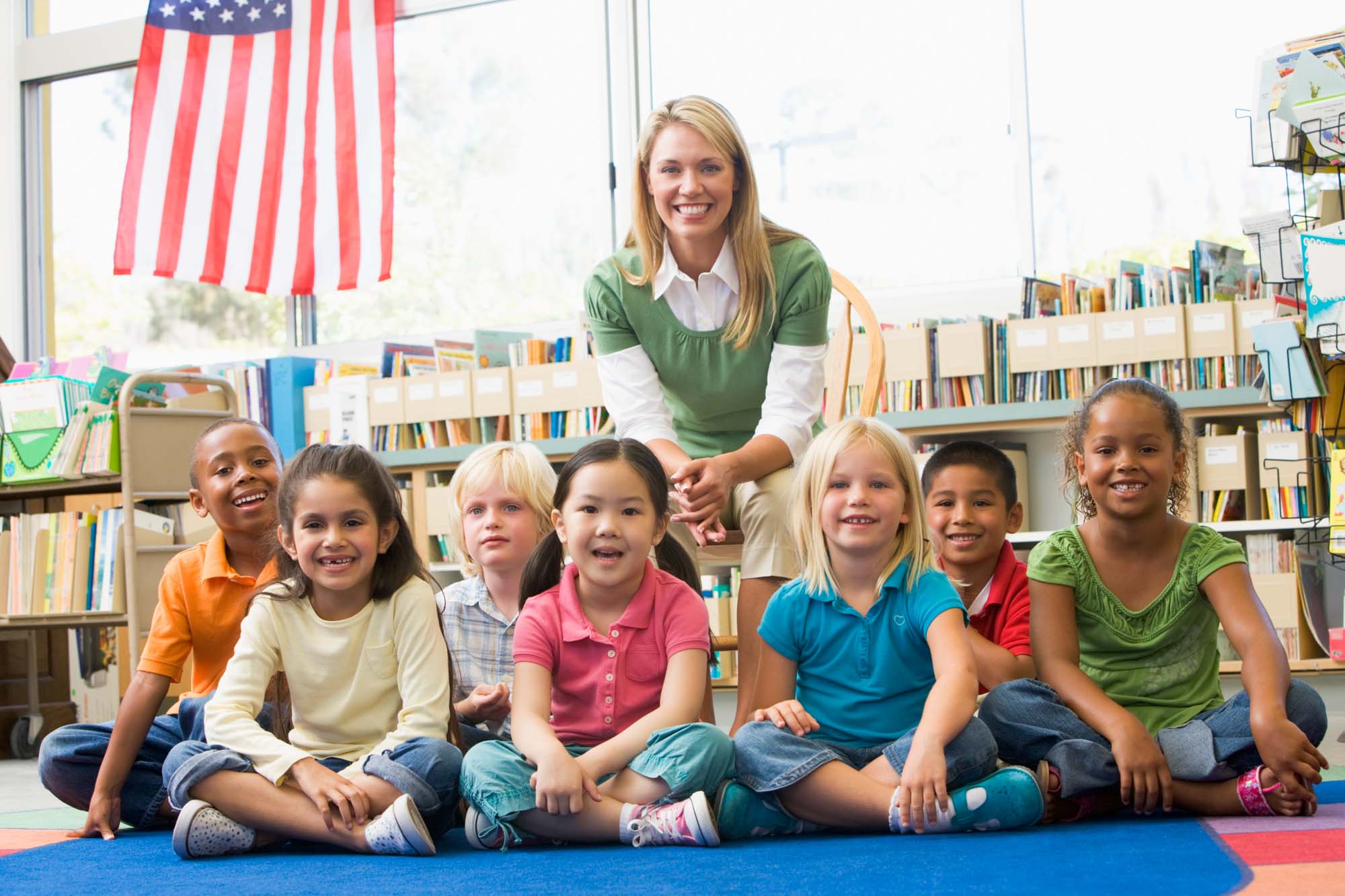 Kindergarten teacher sitting with children in library